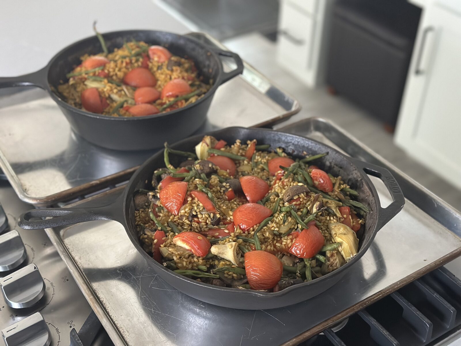 Cast iron skillet with golden saffron rice, blistered tomatoes, green beans, and artichoke hearts