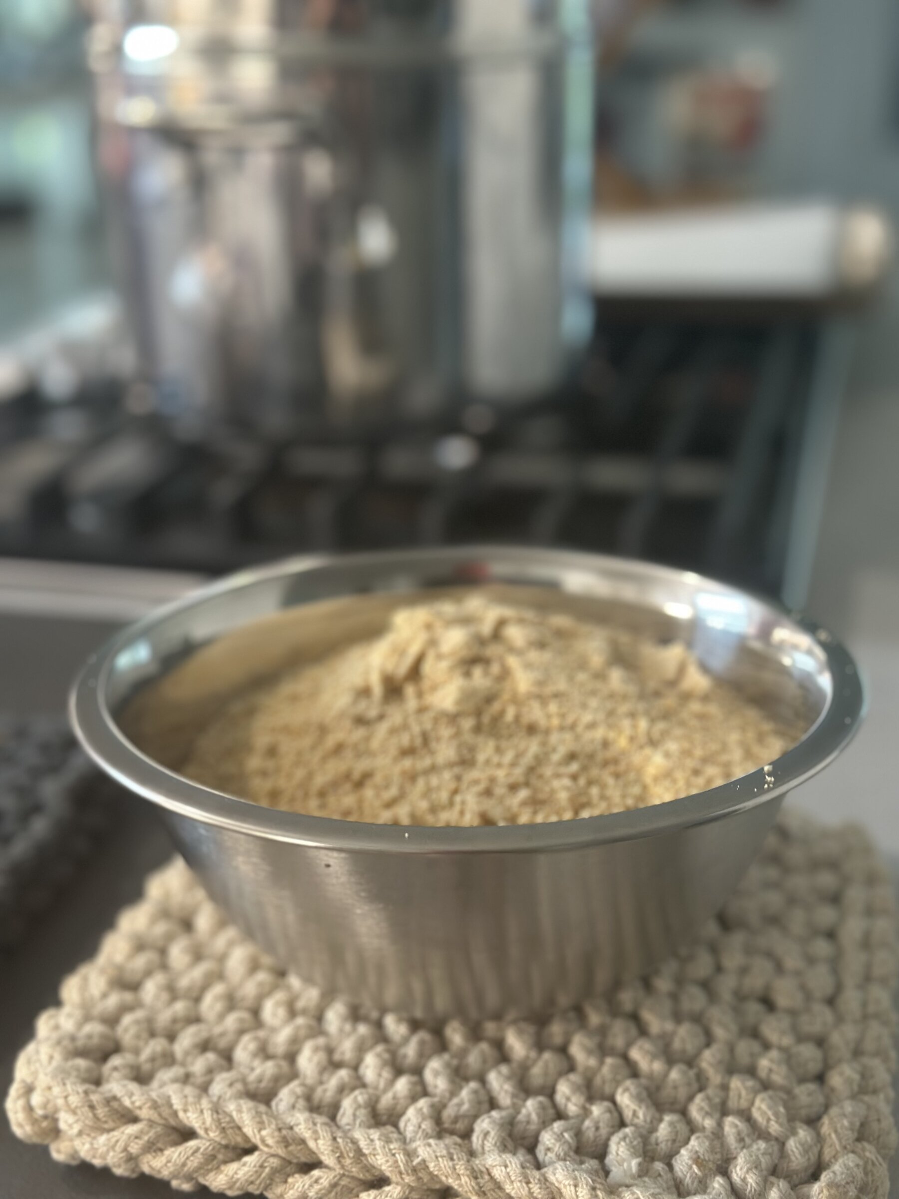 A steel bowl filled with golden, finely ground cashew parmesan
